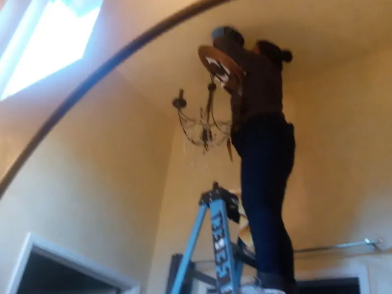 Electrician installing a chandelier in a Prunedale residence